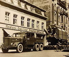Der Culemeyer im Einsatz: Hier zieht er ein Riesenaggregat der AEG vom Güterbahnhof durch die Schulstraße zum Kunden. Im Hintergrund die Marinefrabrik Rostock, die später C&A wich. Heute steht dort ein Wohnblock inklusive Postbank. (Foto: Per Koopmann / Stadtarchiv)  