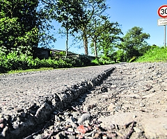 Der Bullendorfer Weg in Elmshorn: Neben der Betonspur klafft eine mehrere Zentimeter tiefe Kante. Es gilt Tempo 30. Das Verkehrsschild weist auf Straßenschäden hin. (Foto: Frank)